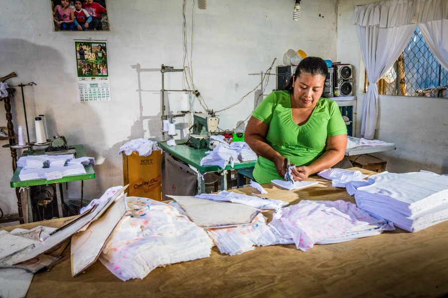 Ana Nieto cutting baby clothes by hand.