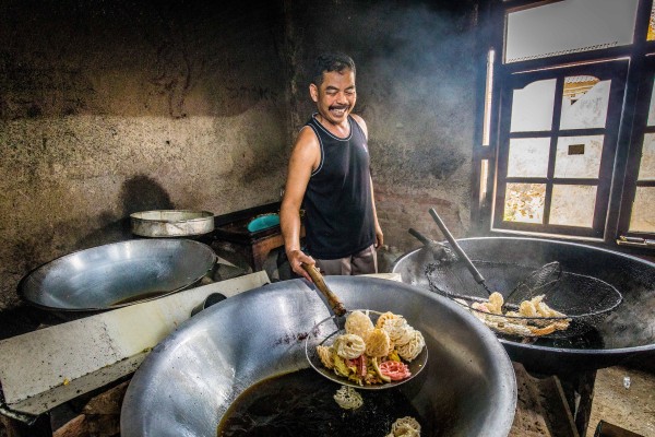 Ajo Among frying krupuk in large woks bought with his wife’s first loan from Komida