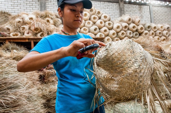 An employee of Concreces client Sombreros Sanchez cutting excess straw from the straw hats it produces. Sombreros Sanchez works with local suppliers to ensure its strong social impact.
